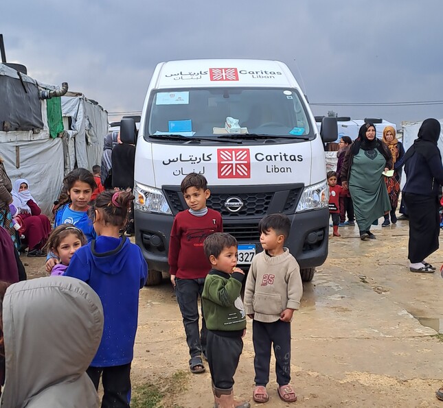 Kinder stehen vor einem Bus mit Caritas-Logo