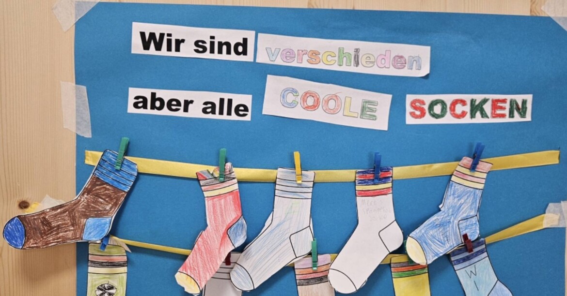 Selbstgestaltete Socken mit Botschaft „Wir sind verschieden, aber alle coole Socken“ an Tafel
